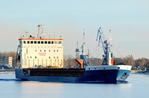 Cargo ship leaving port with lighthouse at the background — Stock Photo, Image