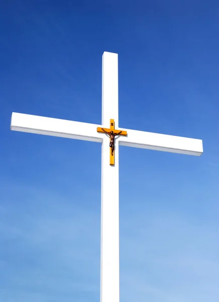 Catholic cross with crusifixion sign against blue sky — Stock Photo, Image