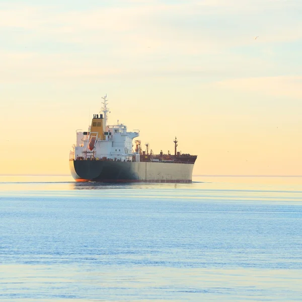 Cargo ship sailing away at the colorful sunset — Stock Photo, Image