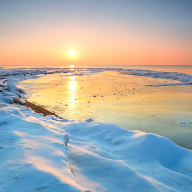 karlı Baltık Denizi sahilinde renkli günbatımı