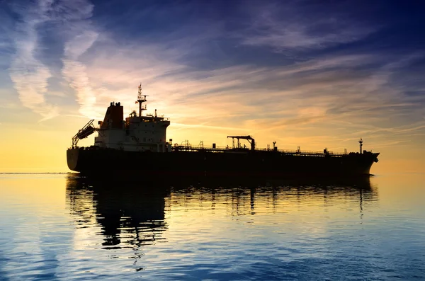 カラフルな夕日を眺めながら出航する貨物船 — ストック写真