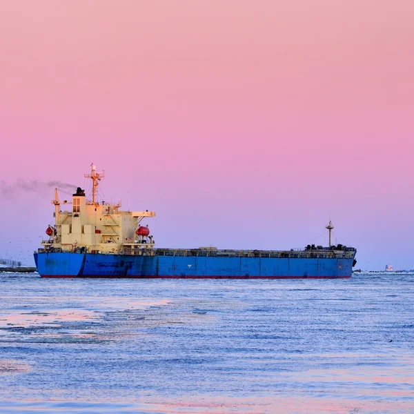 Nave da carico in partenza dal porto con faro sullo sfondo — Foto Stock