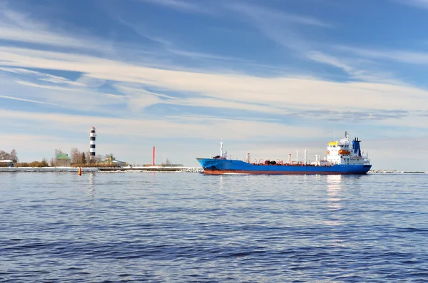 Nave da carico che entra in porto con faro sullo sfondo — Foto Stock