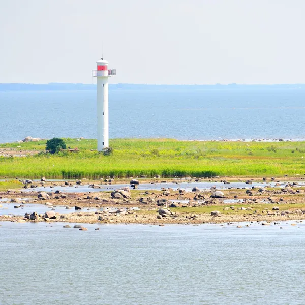 Phare blanc sur l'île rocheuse en mer bleue — Photo