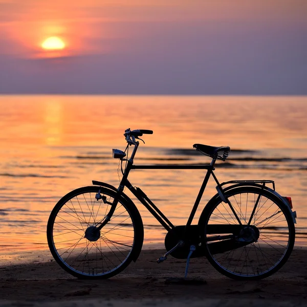 Antigua bicicleta de época en la playa contra el atardecer en el mar — Foto de Stock