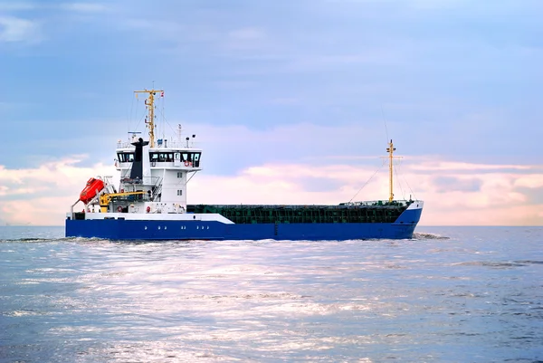 Navio de carga que navega rumo ao pôr do sol — Fotografia de Stock