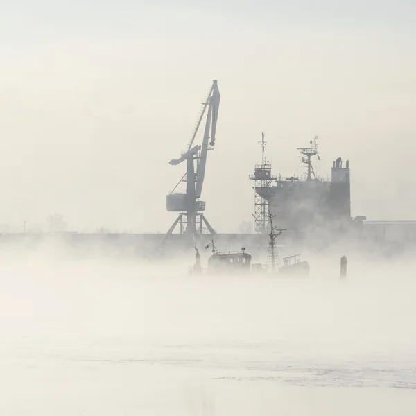 Navio de carga e guindastes silhuetas no nevoeiro — Fotografia de Stock