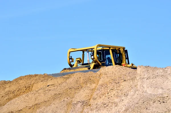 Small yellow bulldozer working in sand dunes — Stock Photo, Image