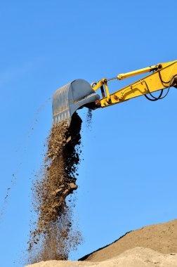 Yeni sarı ekskavatör kum tepeleri üzerinde çalışıyor. Kepçe yakın çekim