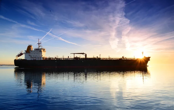 Cargo ship sailing away at the colorful sunset