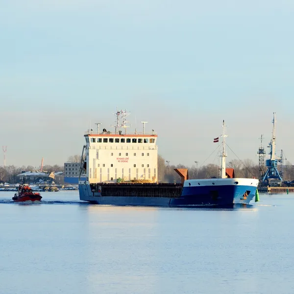 Nave da carico in partenza dal porto con faro sullo sfondo — Foto Stock