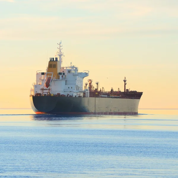 Vrachtschip varen weg bij de kleurrijke zonsondergang — Stockfoto