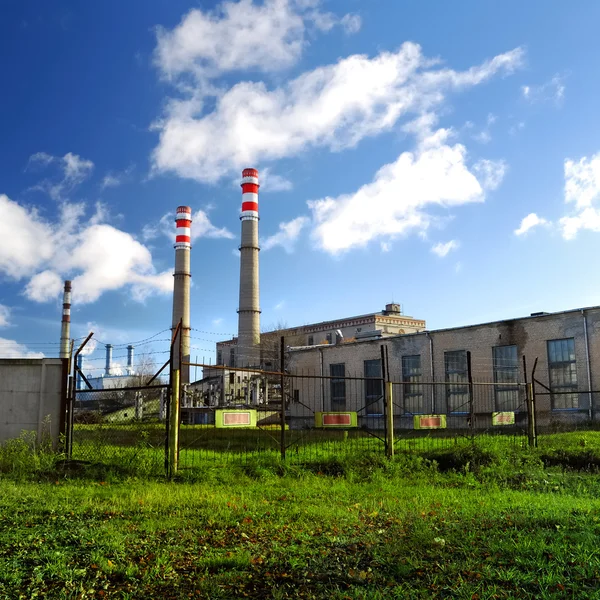 Industrial factory producing electricity with pipes against blue sky — Stock Photo, Image
