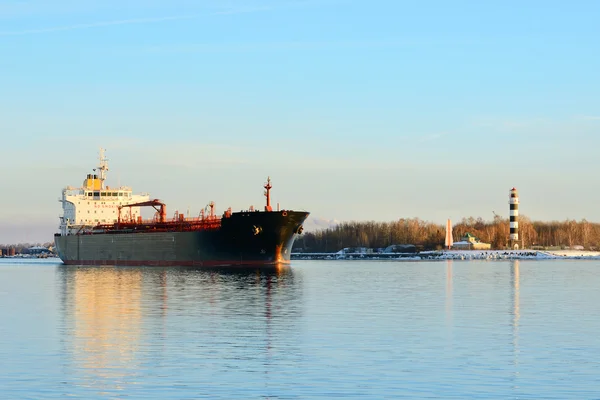 Nave da carico in partenza dal porto con faro sullo sfondo — Foto Stock