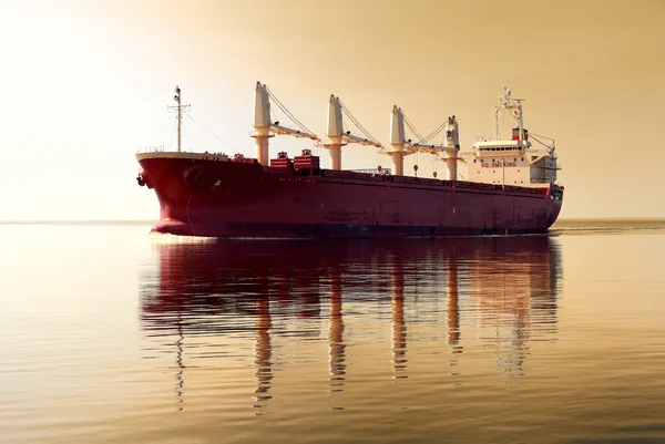 Nave da carico generale con gru che navigano in acque tranquille. Cielo dorato al tramonto. Vista panoramica. Trasporto merci, nave nautica, comunicazioni globali, industria, trasporto, logistica, commercio — Foto Stock