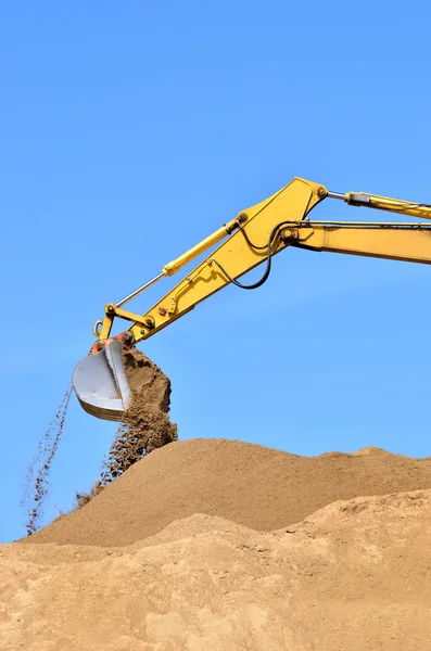 Yeni sarı ekskavatör kum tepeleri üzerinde çalışıyor. Kepçe yakın çekim — Stok fotoğraf