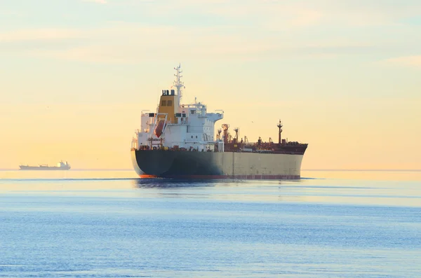 カラフルな夕日を眺めながら出航する貨物船 — ストック写真