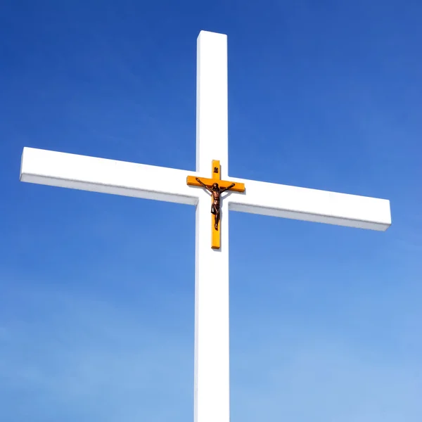 Catholic cross with crusifixion sign against blue sky — Stock Photo, Image