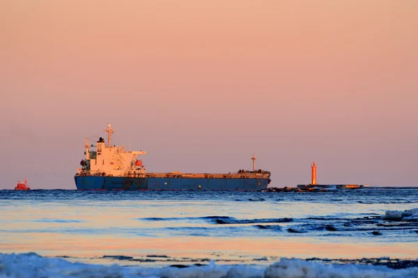 Nave da carico in partenza dal porto con faro sullo sfondo — Foto Stock