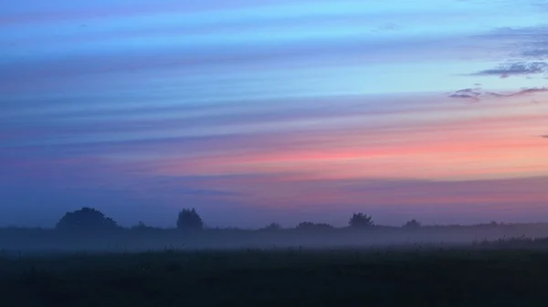 Красочный восход солнца на поле с утренним туманом — стоковое фото