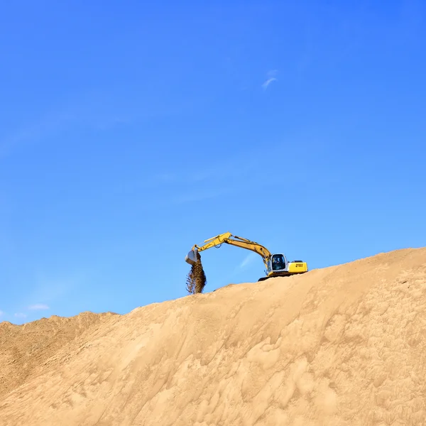 Nueva excavadora amarilla trabajando en dunas de arena —  Fotos de Stock