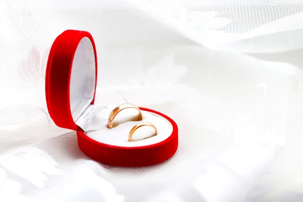 Dos anillos de boda en caja roja sobre fondo abstracto blanco —  Fotos de Stock