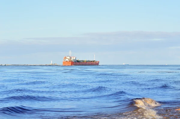 Navire cargo quittant le port avec phare à l'arrière-plan — Photo