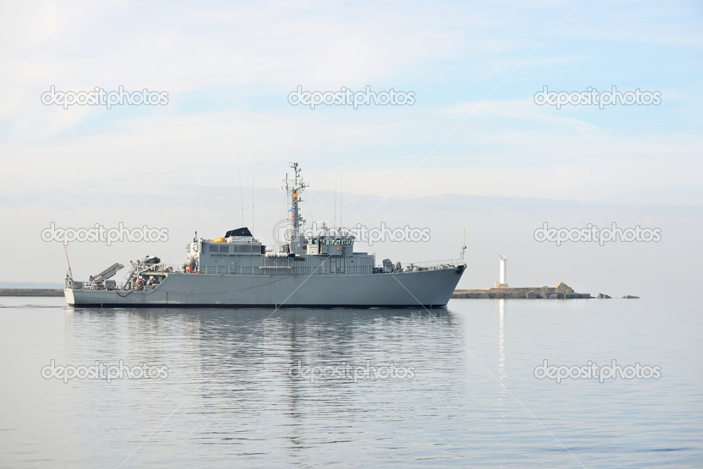 Grey modern warship sailing in still water