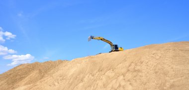 Yeni sarı ekskavatör kum tepeleri üzerinde çalışma
