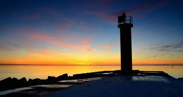 Vuurtoren in de zee bij de kleurrijke zonsondergang — Stockfoto