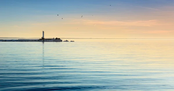 Маяк в море на красочном закате — стоковое фото