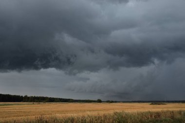 Dramatik gökyüzü, zirai tarlaların ve ormanların üzerindeki kara bulutlar. Kırsal alan. Atmosferik manzara. Sonbaharın başında. Doğa, kararsız hava, ekoloji, çevre, tarım endüstrisi, uzak yerler