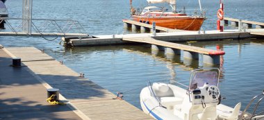 Yat limanındaki bir rıhtıma demirlemiş ahşap meşe güverteli zarif bir modern yelkenli tekne. Deniz aracı, ulaşım, spor, yelkenli yarışı, dinlenme, boş zaman aktivitesi, gezi, tatiller, yaşam tarzı temaları