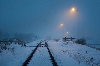 Geceleri karla kaplı demiryolu aydınlanıyor. Atmosferik kış manzarası. Gizemli mavi ışık. Ulaşım. Güvenlik, tehlike kavramları