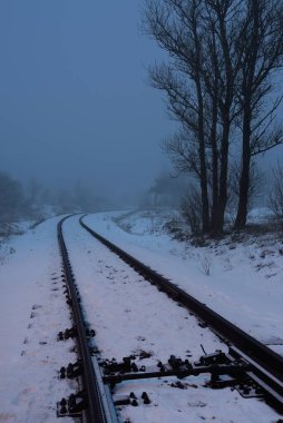 Geceleri karla kaplı demiryolu aydınlanıyor. Atmosferik kış manzarası. Gizemli mavi ışık. Ulaşım. Güvenlik, tehlike kavramları