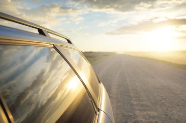 Fırtınadan sonra tarladan geçen boş köy yolu. Arabadan bir manzara. Idyllic kırsal kesim. Renkli, parlayan günbatımı bulutları. Ulaşım, yolculuk, özgürlük, seyahat tutkusu, uzak yerler kavramları.