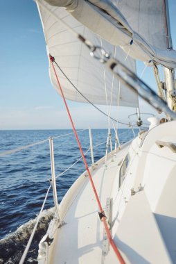 Gün batımında açık denizde yelkenli yelkenli yelkenli. Gökyüzü açık. Güverteden pruvaya bir manzara, direk, yelkenler. Ulaşım, seyahat, gezi, spor, eğlence, boş zaman aktivitesi, yarış, yelkenli yarışı