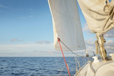 Gün batımında açık denizde yelkenli yelkenli yelkenli. Gökyüzü açık. Güverteden pruvaya bir manzara, direk, yelkenler. Ulaşım, seyahat, gezi, spor, eğlence, boş zaman aktivitesi, yarış, yelkenli yarışı