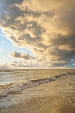 Fırtınadan sonra Baltık kıyıları (kum tepeleri, plaj). Gün batımı, yumuşak altın güneş ışığı, parlayan bulutlar. Resimli panoramik manzara. Doğa, çevre, ekoloji, eko-turizm, yürüyüş, keşif kavramları