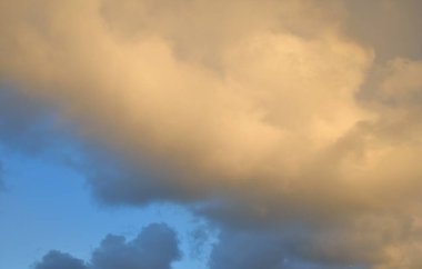 Açık mavi gökyüzü, pembe ve altın rengi sirrus ve günbatımında fırtına üstüne kümülüs bulutları. Dramatik bulut manzarası. Sanat, meteoroloji, cennet, umut, barış, grafik kaynakları, resimli panoramik manzara