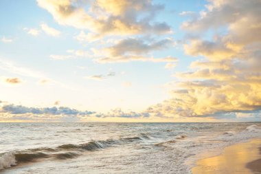 Fırtınadan sonra Baltık kıyıları (kum tepeleri, plaj). Gün batımı, yumuşak altın güneş ışığı, parlayan bulutlar. Resimli panoramik manzara. Doğa, çevre, ekoloji, eko-turizm, yürüyüş, keşif kavramları