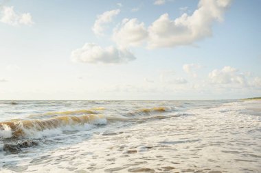 Fırtınadan sonra Baltık kıyıları. Gün batımı, yumuşak altın güneş ışığı. Su yüzeyi dokusu, çarpan dalgalar ve sıçramalar. Resimli panoramik manzara. Idyllic deniz manzarası. Doğa, çevre, ekoloji temaları