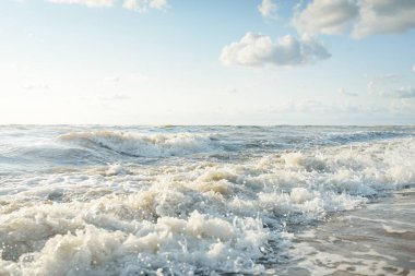 Fırtınadan sonra Baltık kıyıları. Gün batımı, yumuşak altın güneş ışığı. Su yüzeyi dokusu, çarpan dalgalar ve sıçramalar. Resimli panoramik manzara. Idyllic deniz manzarası. Doğa, çevre, ekoloji temaları