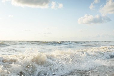 Fırtınadan sonra Baltık kıyıları. Gün batımı, yumuşak altın güneş ışığı. Su yüzeyi dokusu, çarpan dalgalar ve sıçramalar. Resimli panoramik manzara. Idyllic deniz manzarası. Doğa, çevre, ekoloji temaları