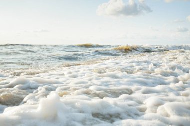 Fırtınadan sonra Baltık kıyıları. Gün batımı, yumuşak altın güneş ışığı. Su yüzeyi dokusu, çarpan dalgalar ve sıçramalar. Resimli panoramik manzara. Idyllic deniz manzarası. Doğa, çevre, ekoloji temaları