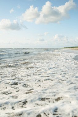 Fırtınadan sonra Baltık kıyıları. Gün batımı, yumuşak altın güneş ışığı. Su yüzeyi dokusu, çarpan dalgalar ve sıçramalar. Resimli panoramik manzara. Idyllic deniz manzarası. Doğa, çevre, ekoloji temaları