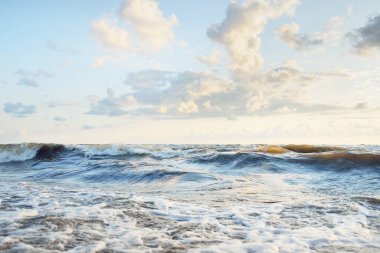 Fırtınadan sonra Baltık kıyıları. Gün batımı, yumuşak altın güneş ışığı. Su yüzeyi dokusu, çarpan dalgalar ve sıçramalar. Resimli panoramik manzara. Idyllic deniz manzarası. Doğa, çevre, ekoloji temaları