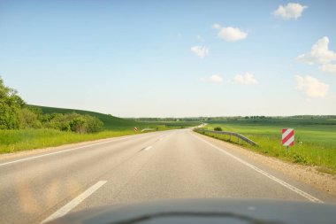 Güneşli bir günde yeşil tarlalarda ve ormanlarda araba sürmek. Açık mavi gökyüzü. Idyllic kırsal alanı, konsept manzarası. Doğa, uzak yerler, lojistik, yaz tatili, yol gezisi