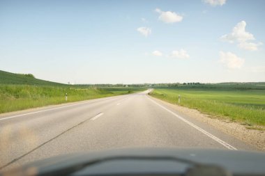 Güneşli bir günde yeşil tarlalarda ve ormanlarda araba sürmek. Açık mavi gökyüzü. Idyllic kırsal alanı, konsept manzarası. Doğa, uzak yerler, lojistik, yaz tatili, yol gezisi