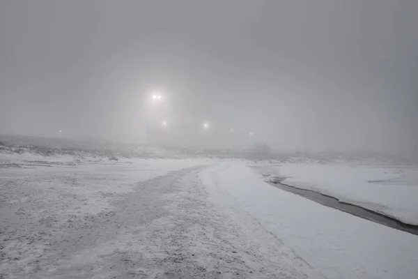 ライトアップされた雪に覆われたバルト海の海岸 背後のポートターミナル 黒と白の冬の風景 生態系 環境被害 燃料と発電の概念 — ストック写真